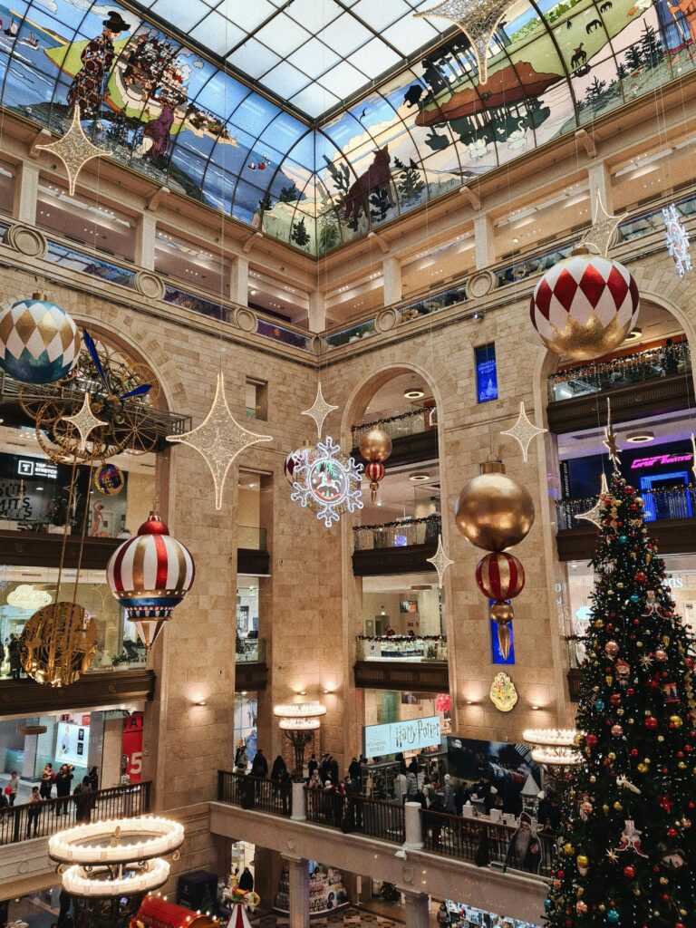 Festive indoor mall adorned with colorful Christmas ornaments and large holiday tree.
