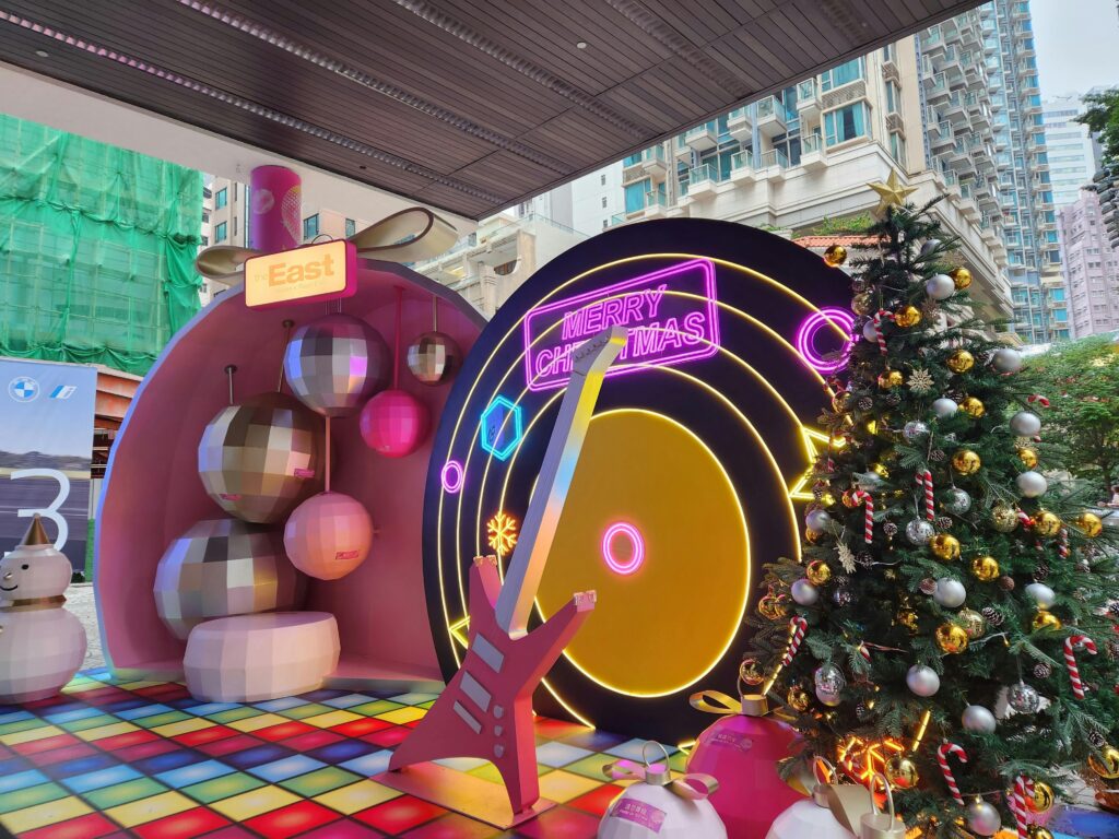 Vibrant Christmas setup in Hong Kong featuring neon signs and a decorated tree for a festive celebration.